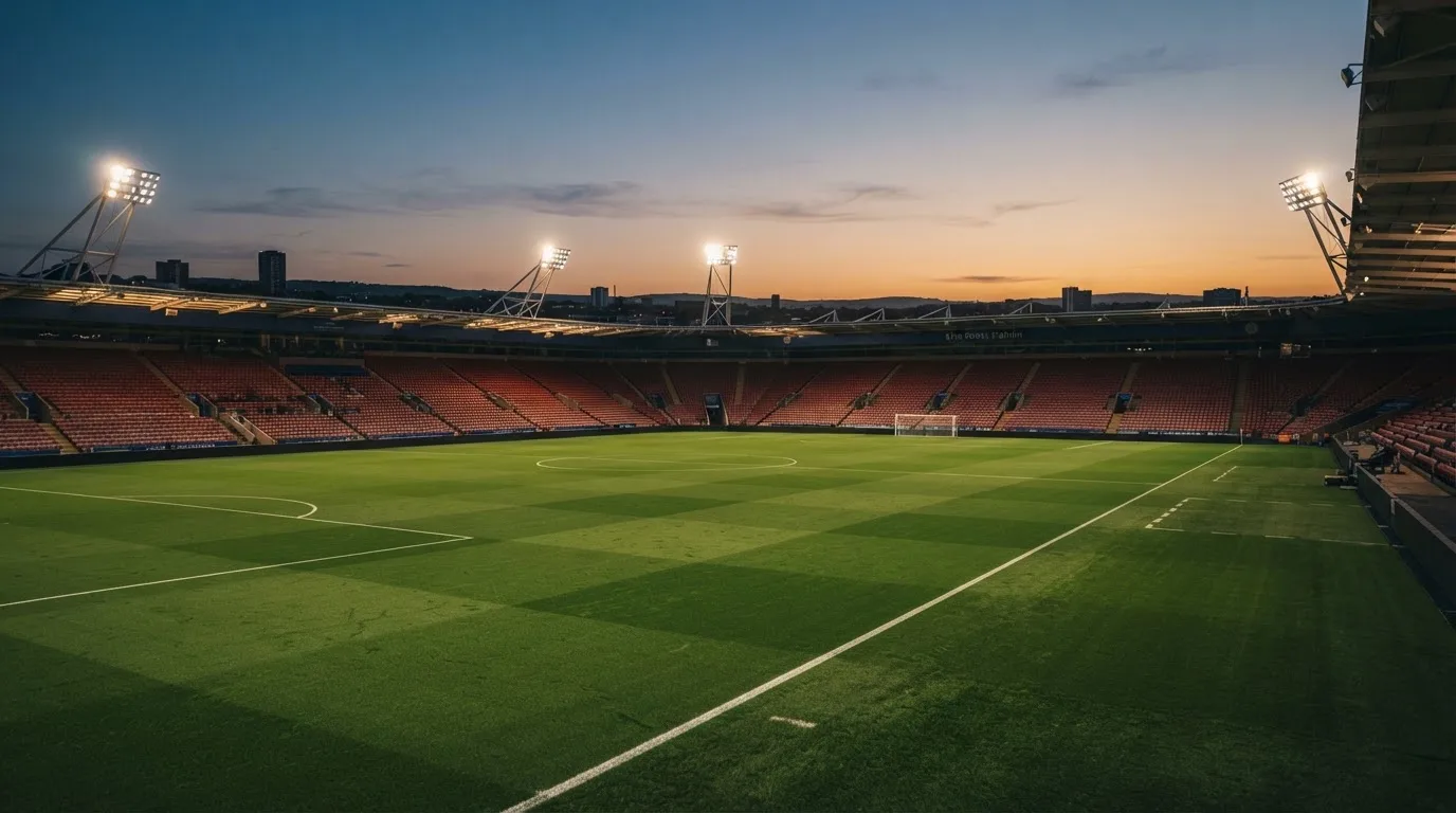 Een leeg voetbalstadion met lichtmasten bij schemering