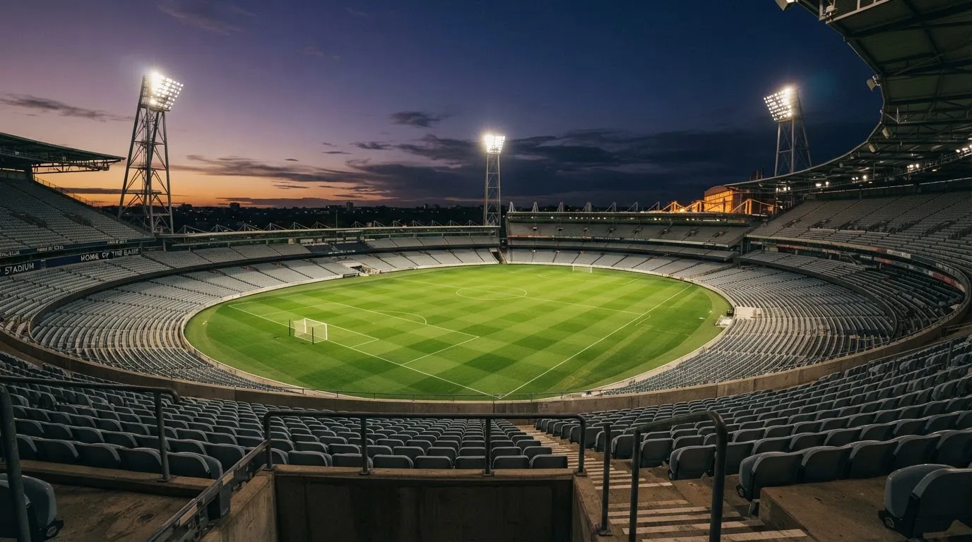 Een leeg voetbalstadion met lichtmasten bij schemering