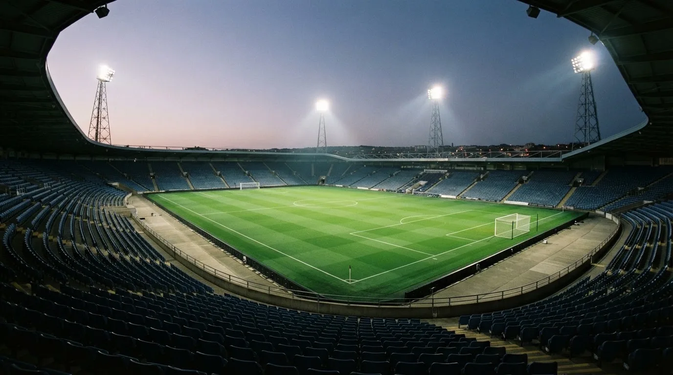 Een leeg voetbalstadion met lichtmasten bij schemering