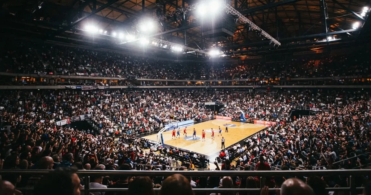 Een volle sporthal onder schijnwerpers, van grote afstand gefotografeerd