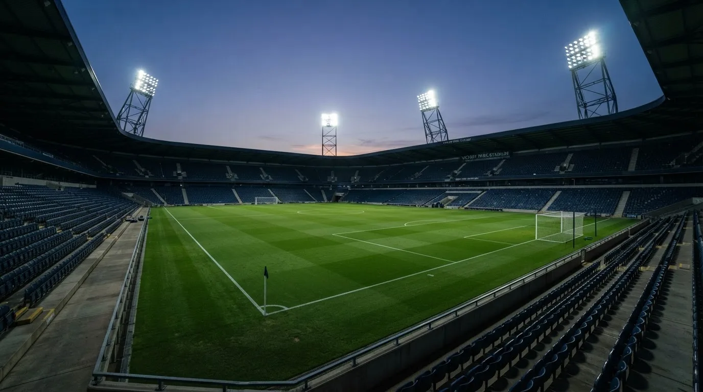 Een leeg voetbalstadion met lichtmasten bij schemering