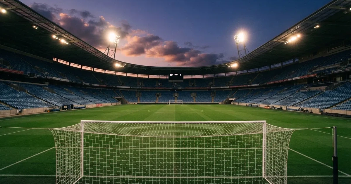 Een leeg voetbalstadion met lichtmasten bij schemering