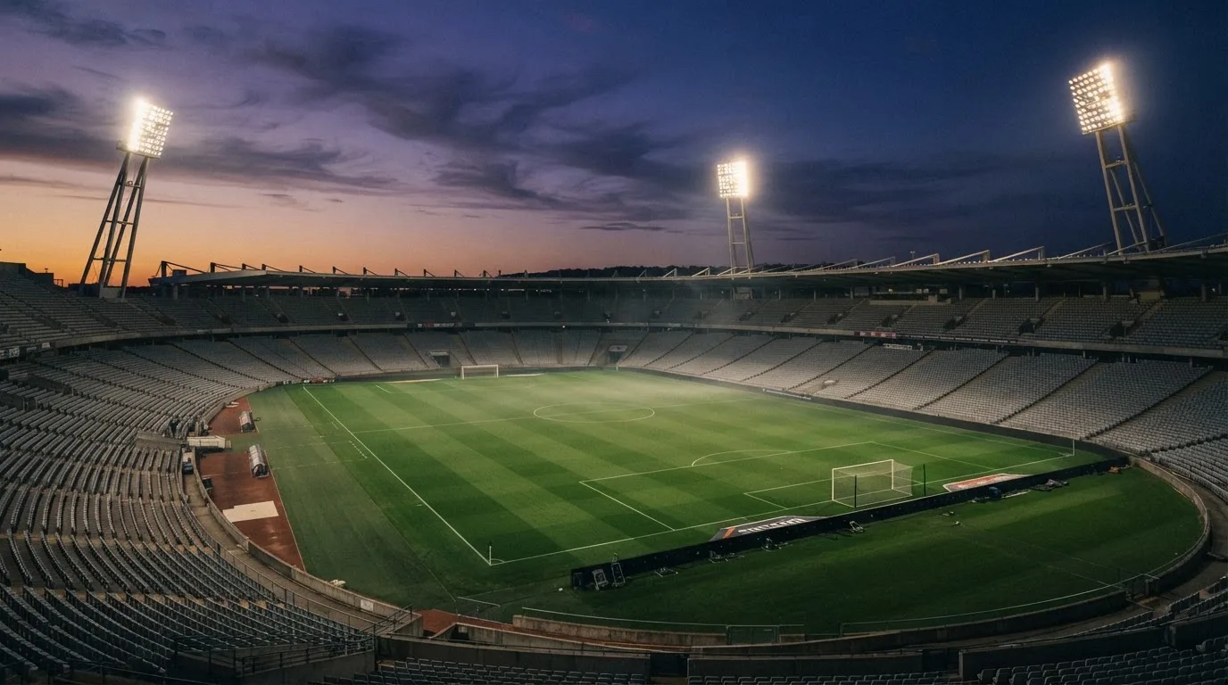 Een leeg voetbalstadion met lichtmasten bij schemering
