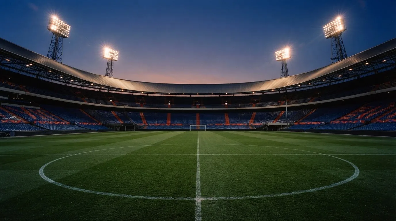 Een leeg voetbalstadion met lichtmasten bij schemering