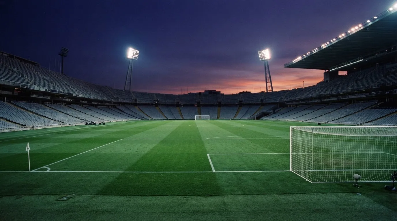 Een leeg voetbalstadion met lichtmasten bij schemering