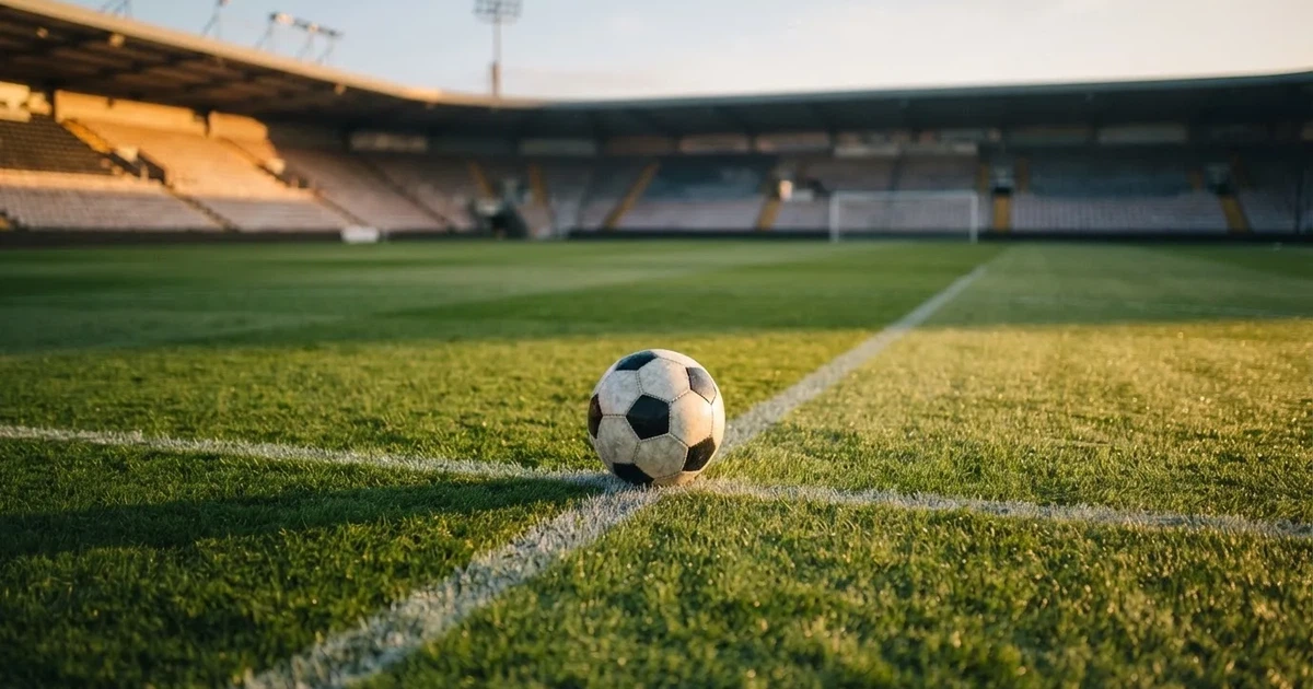 Een voetbal op de middenstip van een grasveld in het ochtendlicht