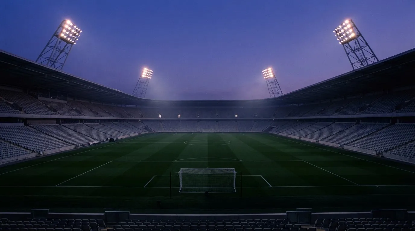 Een leeg voetbalstadion met lichtmasten bij schemering