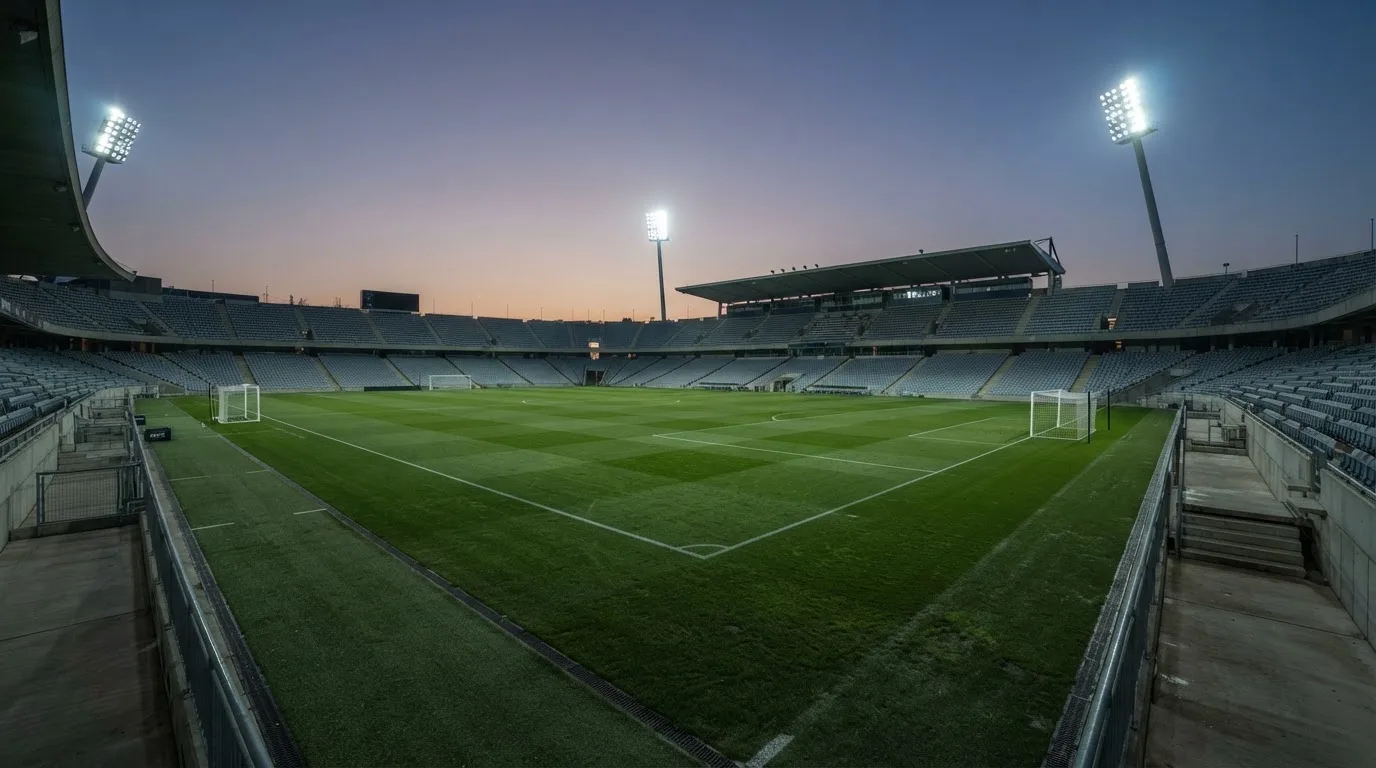 Een leeg voetbalstadion met lichtmasten bij schemering