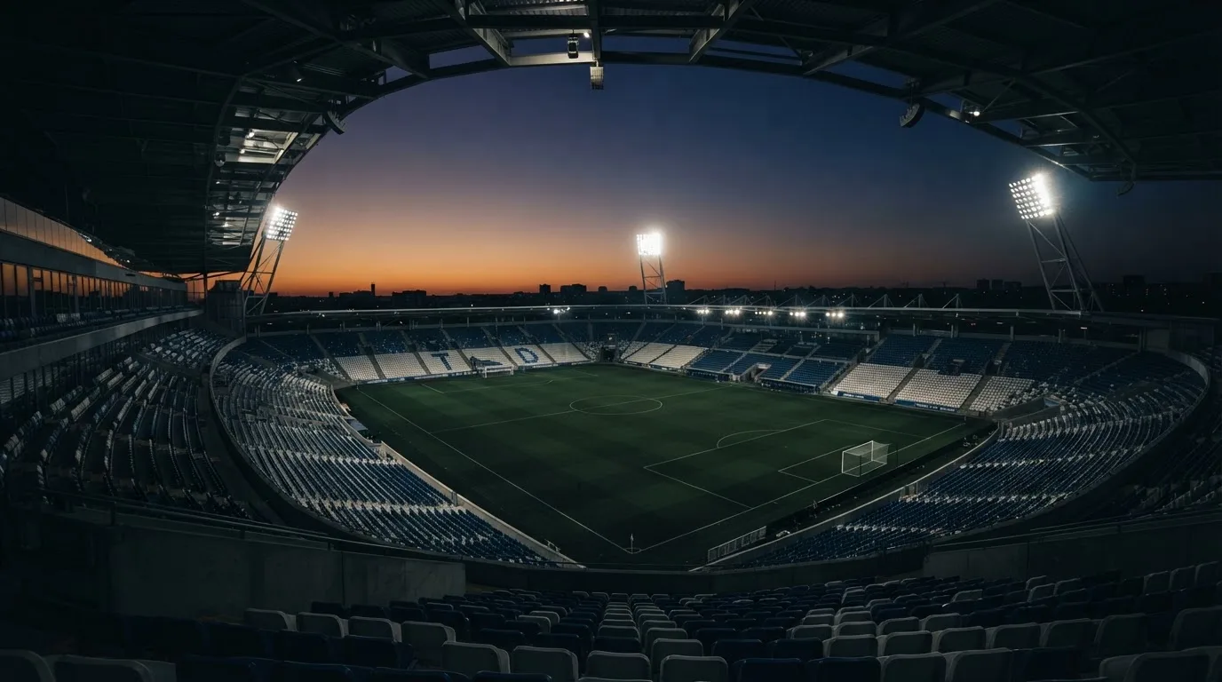Een leeg voetbalstadion met lichtmasten bij schemering