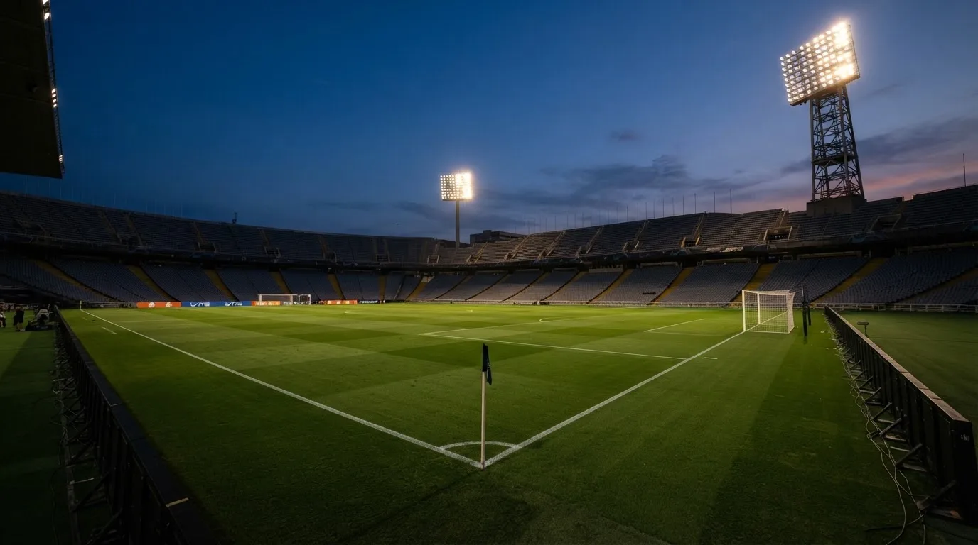 Een leeg voetbalstadion met lichtmasten bij schemering