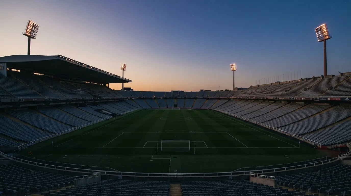 Een leeg voetbalstadion met lichtmasten bij schemering