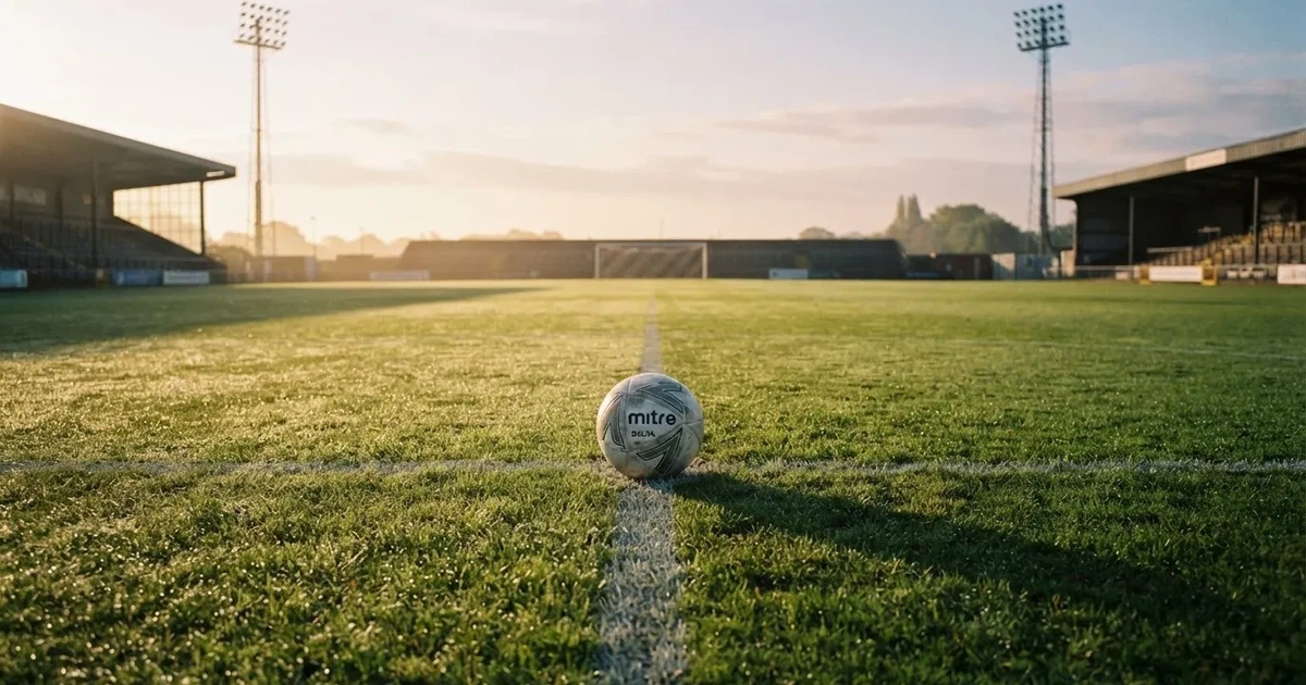 Een voetbal op de middenstip van een grasveld in het ochtendlicht