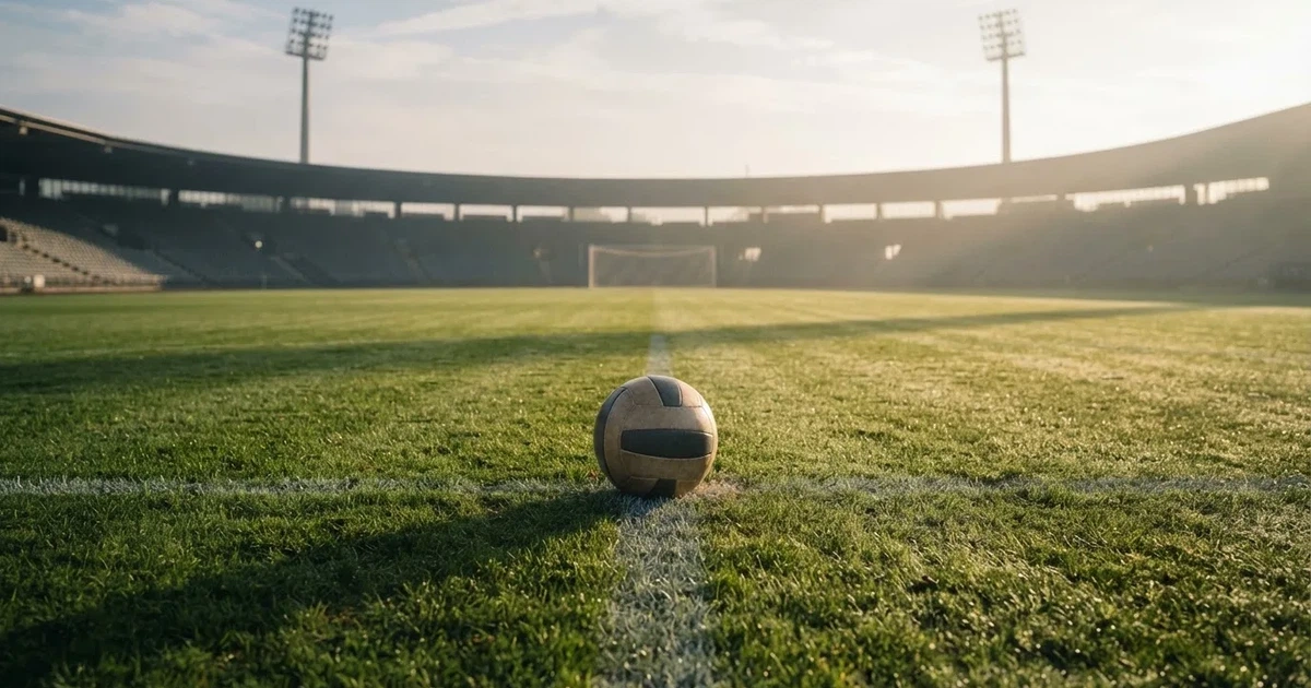 Een voetbal op de middenstip van een grasveld in het ochtendlicht