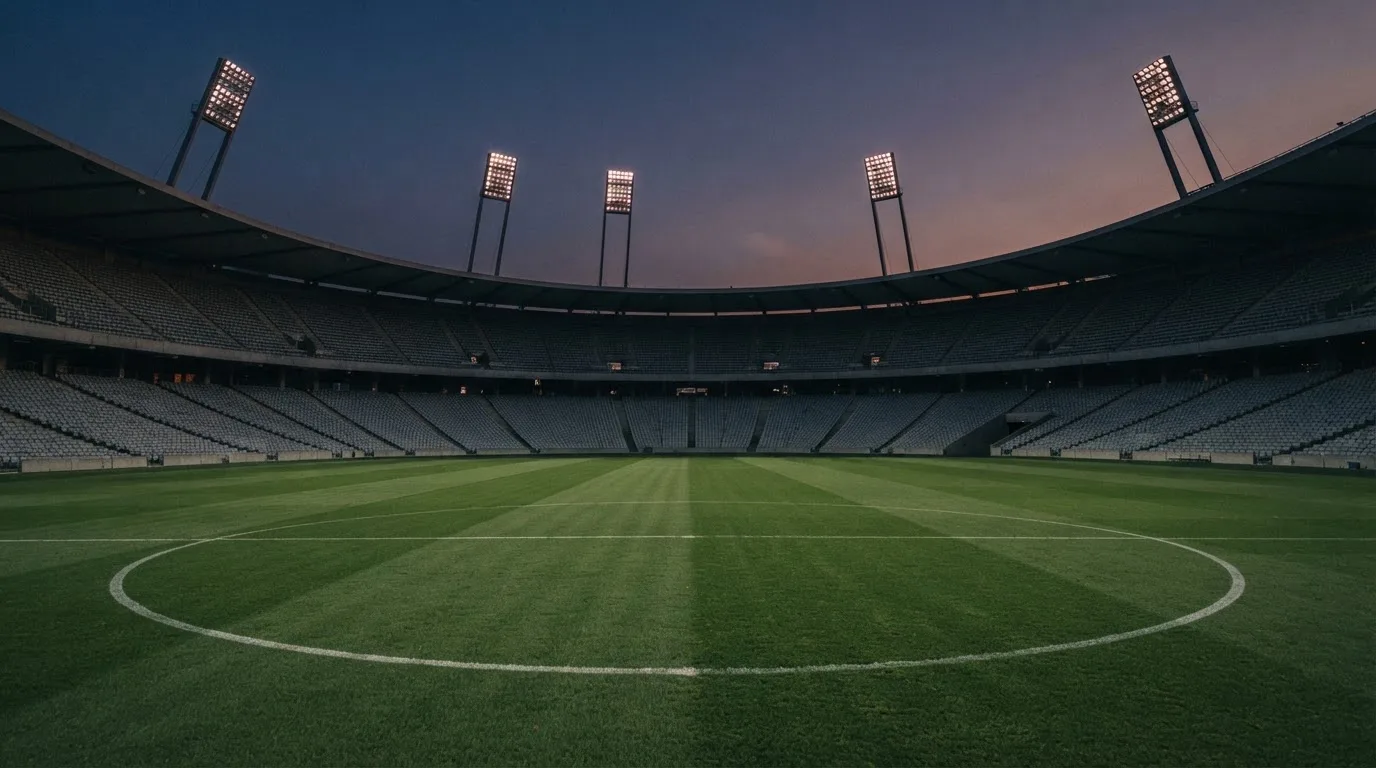 Een leeg voetbalstadion met lichtmasten bij schemering